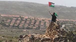 رجل يلوح بالعلم الفلسطيني امام مستوطنة عوفرابجانب رامالله (عصام ريماوي/ فلاش 90)