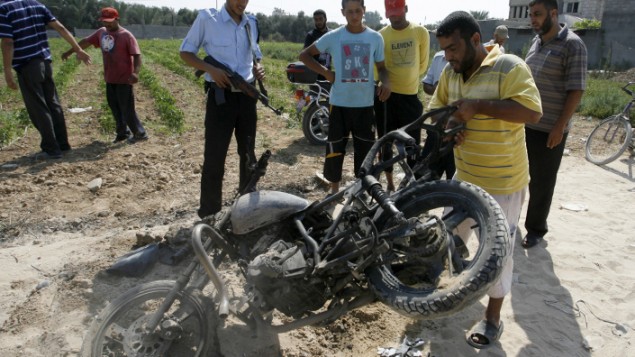 فلسطينيون حول دراجة نارية اصيبت بنيران اسرائيلية في دير البلح في غزة 2012 (عبد الرحيم خطيب / فلاش 90)
