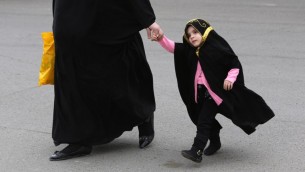 امرأة محجبة مع طفلة مغطاة من رأسها الى أخمص قدميها, مؤيدو القانون يزعمون بانه سوف يشرع العادات التي تمارس يوميا ( بعدسة أحمد الرباعي/ أ ف ب)
