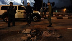 مدنيون ورجال امن اسرائيليين يقفون بجانب حفرة نتجت عن صقوط صاروخ في الصحراء الجنوبية (أ ف ب)