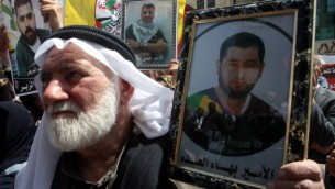مسن فلسطيني يحمل صورة قريبه الاسير في مظاهرة بذكرى يوم الاسير في الخليل ١٧ ابريل ٢٠١٤ (حازم بدر / أ ف ب)