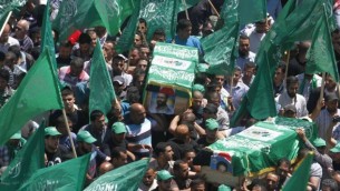 فلسطينيون يرفعون  الراية الخضراء لحركة المقاومة الاسلامية حماس  اثناء جنازة اثنين من أعضاء حماس، عادل وعماد عوض الله، اللذان قتلا بأيدي القوات الإسرائيلية في عام 1998، بعد أن أعادت إسرائيل رفات المقاتلين الفلسطينيين إلى أسرهم لدفنها، في 30 نيسان 2014 (Esam Rimawi/ flash 90)