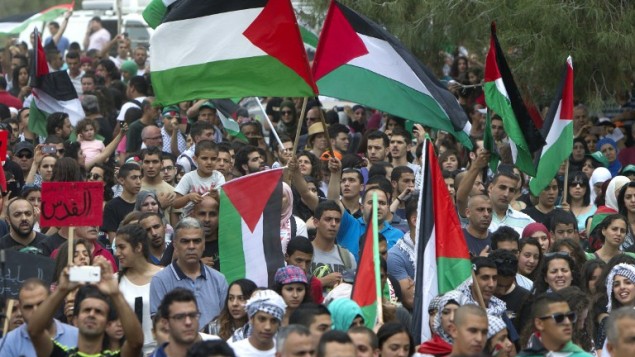 عرب إسرائيلون يصمدون العلم الفلسطيني وهم يسيرون من اجل  حق العودة للاجئين الفلسطينيين الذين فروا من ديارهم أو طردوا أثناء حرب 1948 التي أعقبت قيام دولة إسرائيل، بالقرب من طبرية في شمال إسرائيل، يوم 6 مايو، عام 2014. AFP PHOTO / أحمد غرابلي