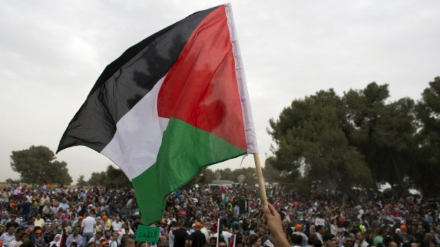 العلم الفلسطيني خلال مسيرة من اجل حق العودة للاجئين الفلسطينيين الذين فروا من ديارهم أو طردوا أثناء حرب 1948 التي أعقبت قيام دولة إسرائيل، بالقرب من طبرية في شمال إسرائيل، يوم 6 مايو، عام 2014. AFP PHOTO / أحمد غرابلي العلم الفلسطيني خلال مسيرة من اجل حق العودة للاجئين الفلسطينيين الذين فروا من ديارهم أو طردوا أثناء حرب 1948 التي أعقبت قيام دولة إسرائيل، بالقرب من طبرية في شمال إسرائيل، يوم 6 مايو، عام 2014. AFP PHOTO / أحمد غرابلي
