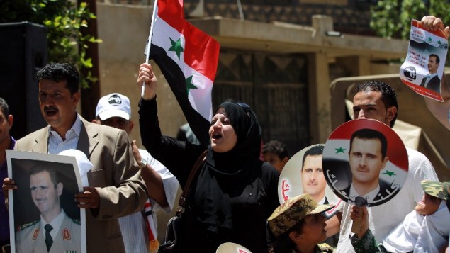 صورا للرئيس السوري بشار الاسد خلال تظاهرة لدعم إعادة انتخابه في 24 مايو 2014 خارج السفارة السورية في العاصمة اليمنية صنعاء.  AFP PHOTO / MOHAMMED HUWAIS
