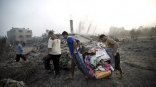 فلسطينيون يحملون اغراضهم بعد غارة اسرائيلية ٨ يوليو ٢٠١٤  AFP/MAHMUD HAMS