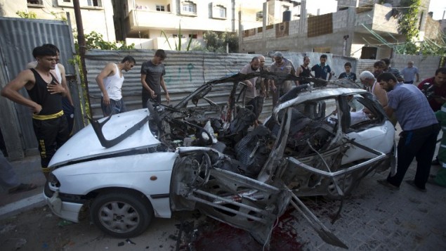فلسطينيون يتفحصون حطام سيارة ضربتها غارة اسرائيلية مما اسفر عن مقتل ٣ عناصر للجهاد الاسلامي ١٠ يوليو ٢٠١٤ (آ ف ب/ محمود حمص)