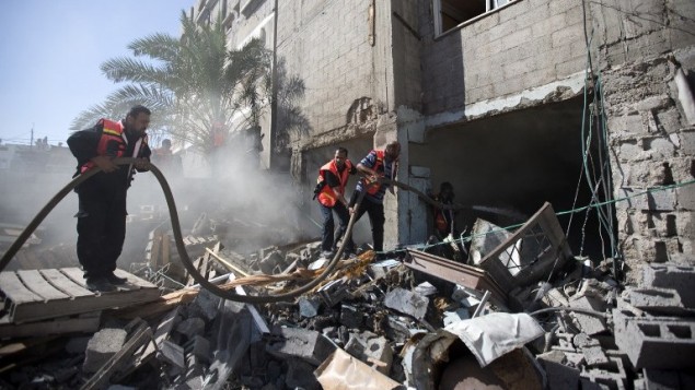 رجال الاطفاء الفلسطينيون في محاولة لاطفاء حريق شب في منزل دمر خلال غارة إسرائيلية، 16 يوليو  2014، في مدينة غزة. AFP PHOTO / MAHMUD HAMS