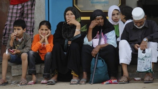 عائلة فلسطينية تجلس على الرصيف بعد فرارهم حيهم إلى موقع أكثر أمانا بعد قصف منطقة خان يونس، في جنوب قطاع غزة،  23 يوليو  2014. AFP PHOTO