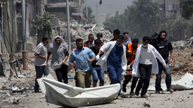 مسعفون يقومون بإخلاء جثة من منطقة الشجاعية شرق غزة  20 يوليو 2014. AFP PHOTO / MAHMUD HAMS