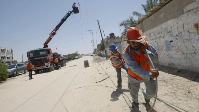 عمال شركة الكهرباء الفلسطينية يعملون على تصليح خطوط الكهرباء التي تم تدميرها في أعقاب ضربة جوية اسرائيلية  في رفح، جنوب قطاع غزة،  6 أغسطس 2014 (AFP/SAID KHATIB)
