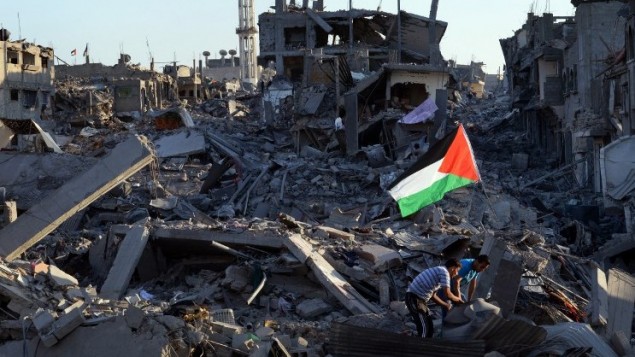 سكان بين أنقاض منزلهم المحطمة ، وعلم الفلسطيني وسط لادمار، في حي الشجاعية في مدينة غزة 7 أغسطس 2014. AFP PHOTO / ROBERTO SCHMIDT