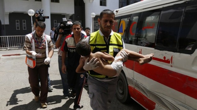 موظف الطوارئ يحمل الطفل الذي أصيب بجروح في غارة جوية إسرائيلية على حي الشيخ رضوان شمال مدينة غزة،  مستشفى الشفاء في المدينة،  8 أغسطس 2014.  AFP PHOTO / MOHAMMED ABED