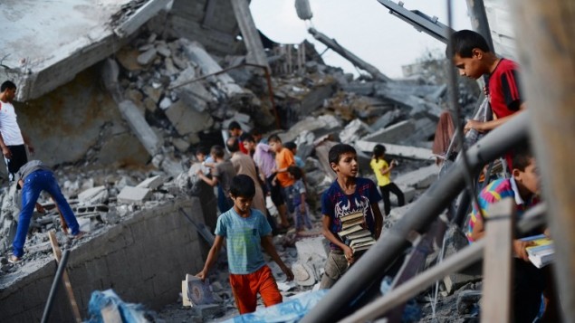 اطفال فلسطينيون يساعدون في البحث عن الكتب الدينية  في المسجد الذي استهدفه القصف الجوي الاسرائيلي في النصيرات في وسط قطاع غزة، في وقت مبكر من 10 أغسطس  2014. AFP PHOTO / ROBERTO SCHMIDT