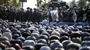 قوات الأمن الإسرائيلية تقف أمام المصلين المسلمين الفلسطينيين وهم يؤدون صلاة الجمعة التقليدية في شارع خارج البلدة القديمة في القدس الشرقية  24 تشرين الأول 2014  
AFP PHOTO / THOMAS COEX