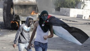 ملثم فلسطيني يلقي حجارة أثناء اشتباكات مع قوات الأمن الإسرائيلية في القدس الشرقية، 30 أكتوبر 2014 AFP/Ahmad Gharabli