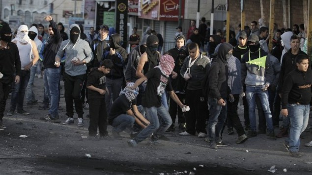 شبان فلسطينيون ملثمون يشتبكون مع قوات الأمن الإسرائيلية في مخيم شعفاط للاجئين الفلسطينيين في القدس الشرقية،  6 نوفمبر 2014.AFP PHOTO/ AHMAD GHARABLI