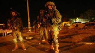 جنود إسرائيليون ينظر عند مدخل قرية فلسطينية العروب، الضفة الغربية، حيث أصيب ثلاثة جنود إسرائيليين بعد ان دهسهم سائق فلسطيني بسيارته على مقربة من مفرق غوش عتصيون، خارج القدس، 5 نوفمبر 2014. Nati Shohat/Flash90