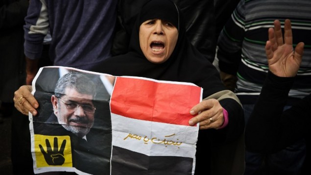 داعمة لتنظيم الاخوان المسلمين تحمل يافطة عليها صورة الرئيس المصري المخلوع محمد مرسي خلال مظاهرة في القاهرة، 24 يناير 2015 (MOHAMED EL-SHAHED / AFP)