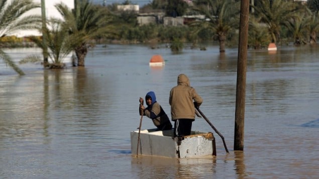 اطفال فلسطينيون يجذفون قارب مرتجل في شارع غمرته المياه في قرية المغراقة جنوب قطاع غزة؛ 22 فبراير 2015  AFP PHOTO / MAHMUD HAMS
