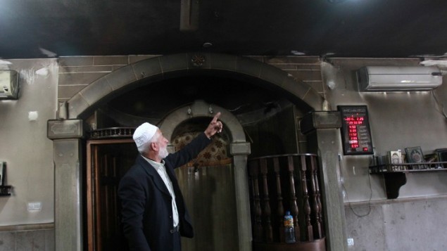 امام فلسطيني يعرض الدمار في المسجد الذي تم احراقه في قرية الجعبة غرب بيت لحم، 25 فبراير 2015 (AFP/MUSA AL-SHAER)