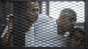23 يونيو 2014 للصحافي في قناة الجزيرة القناة الاسترالي بيتر غريست (L) وزملاؤه، الكندي المصري محمد فاضل فهمي (C) والمصري باهر محمد،  داخل قفص المتهمين خلال المحاكمة AFP PHOTO / KHALED DESOUKI