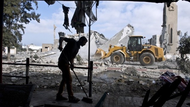 رجل فلسطيني يكنس مدخل بيته الذي تضرر بعد قصف مسجد قريب منه في بيت لاهيا، 25 اغسطس 2014 (AFP Photo/Roberto Schmidt)