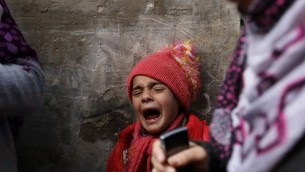 صبي فلسطيني يبكي أثناء تشييع جنازة طفل عمره 9 اشهر، بعد وفاته في حريق جراء تماس كهربائي، في مدرسة للامم المتحدة تستخدم كمأوى للفلسطينيين الذين دمرت منازلهم  في القصف الإسرائيلي  صيف 2014،  بيت حانون ، غزة 17 فبراير، 2015. AFP PHOTO / MOHAMMED ABED