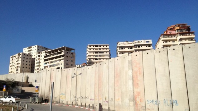 مباني سكنية في راس خميس تعلو فوق الجدار في القدس الشرقية (Elhanan Miller/Times of Israel)