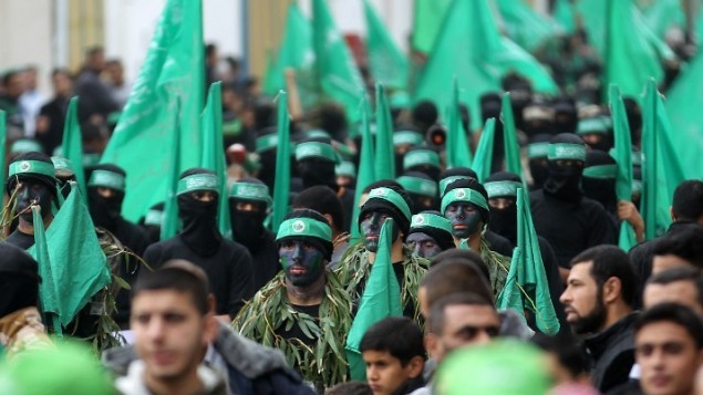 نشطاء فلسطينيون في كتائب عز الدين القسام، الجناح العسكري لحركة حماس، خلال مسيرة لإحياء الذكري ال27 لتأسيس الحركة، في مخيم النصيرات للاجئين وسط غزة في 12 ديسمبر، 2014. ( AFP/ SAID KHATIB)