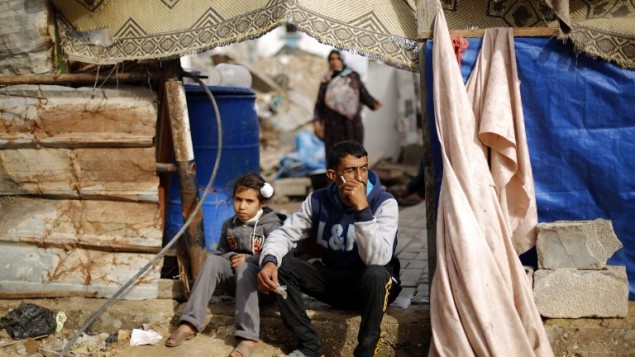رجل وطفلة فلسطينيين امام منزلهم المدمر في بيت حانون شمال قطاع غزة، 4 مارس 2015 (MOHAMMED ABED / AFP)