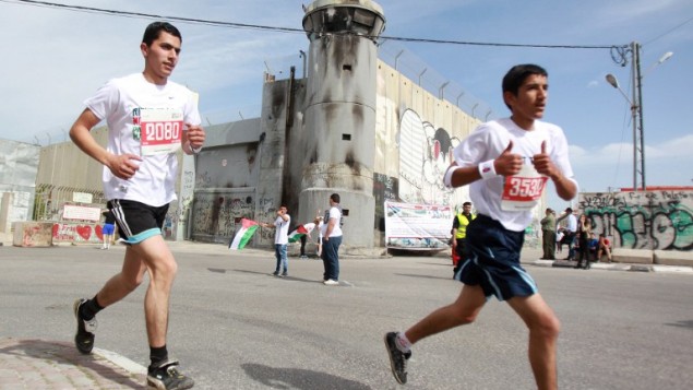 رياضيون فلسطينيون عرب واجانب يركضون على طول الجدار الاسرائيلي المثير للجدل  الثالث ماراثون فلسطين الثالث في  بيت لحم 27 مارس 2015. ووفقا لمسؤولين فلسطينيين قد شارك حوالي 3200 عداء في سباق الماراثون هذا العام  AFP PHOTO / MUSA AL SHAER