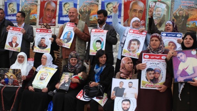 فلسطينيون يحملون صور اقربائهم المعتقلين في السجون الإسرائيلية خلال مظاهرة امام مكتب الصليب الأحمر في رام الله، 15 ابريل 2014 (Issam Rimawi/FLASH90