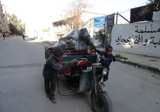 اطفال مع عربة محملة في شوارع مخيم اليرموك، 4 ابريل 2015 (RAMI AL-SAYED / AFP)