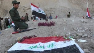 مقاتل عراقي شيعي يصلي في موقع يعتقد انه مقبرة جماعية لضحايا مجزرة سبايكر في مدينة تكريت العراقية، 4 ابريل 2015 (AHMAD AL-RUBAYE / AFP)
