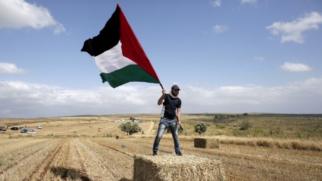 عربي من اسرائيل العرب يحمل العلم الفلسطيني خلال مسيرة العودة السنوية من اجل حق العودة للاجئين الفلسطينيين الذين فروا من ديارهم أو طردوا خلال حرب عام 1948. مسيرة هذا العام الى قرية الحدثة بالقرب من طبريا في شمال إسرائيل،  23 أبريل عام 2015. AFP PHOTO / AHMAD GHARABLI
