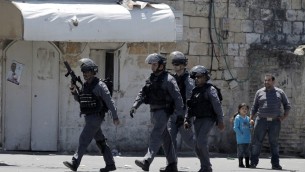 طفلة فلسطينية ورجل فلسطيني يقفون بينما يعبر عناصر قوات الامن الاسرائيلي خلال الموجهات في حي الطور بعد ان قتلت الشرطة فلسطيني يبلغ ال 17 من العمر 25 ابريل 2015  AFP PHOTO / AHMAD GHARABLI