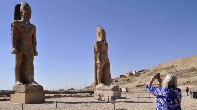 سائحة تلتقط صورة لتمثالين ضخمين للفرعون أمنحتب الثالث في المعبد الشهير في  مدينة الأقصر المصرية، 14 ديسمبر، 2014. (AFP/Radwan Abu Elmagd)