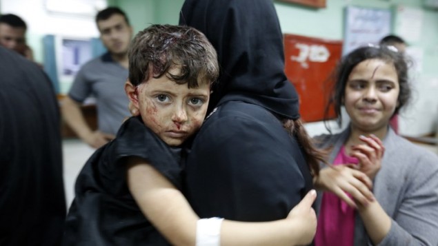 امرأة فلسطينية تحمل طفلها المصاب داخل مستشفى في بيت لاهيا بعد وقوع انفجار في مقر تابع لحماس، 14 مايو 2015 (MOHAMMED ABED / AFP)