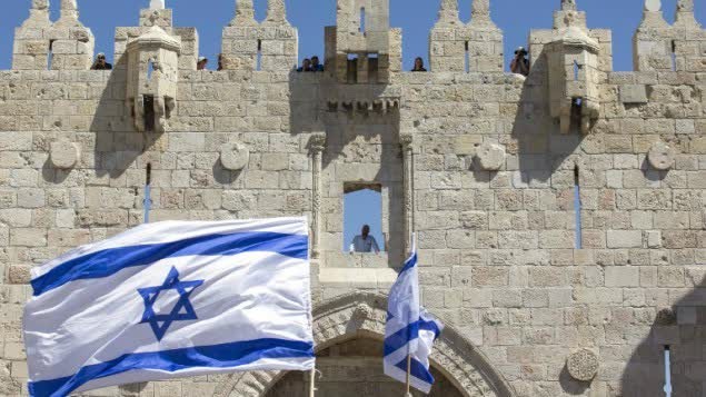 شباب يهود يلوحون بأعلام اسرائيل خلال مسيرة العلم في باب العامود في البلدة القديمة في القدس ضمن احتفالات يوم القدس، 17 مايو 2015 (AFP Photo/Jack Guez)