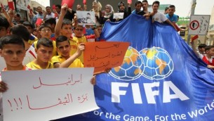 شباب فلسطينيون يحملون لافتات حمراء كتب عليها باللغة العربية "اسرائيل خارج الفيفا" خلال مظاهرة ضد الاتحاد الاسرائيلي لكرة القدم في مدينة الخليل بالضفة الغربية،  28 مايو، 2015 AFP photo/Hazem Bader