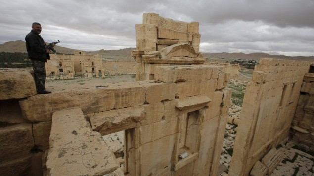 (ارشيف) شرطي سوري يقف فوق معبد بعل في مدينة تدمر الأثرية، 14 مارس 2015 (JOSEPH EID / AFP)