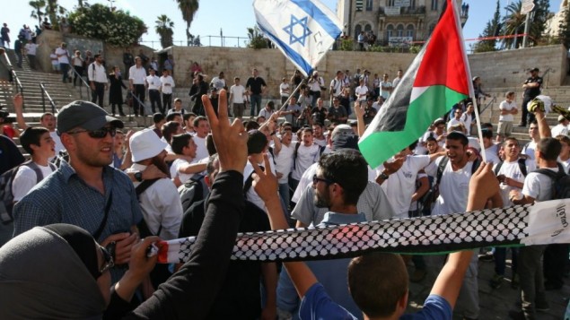 الفلسطينيون يتظاهرون في الوقت الذي يحتفل به فتية يهود ب"يوم القدس" في باب العامود بالبلدة القديمة، 17 مايو، 2015. (Nati Shohat/Flash90)