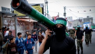 نشطاء ملثم في حركة حماس يعرض صاروخ خلال مسيرة لإحياء الذكري ال27 لتأسيس الحركة، في مخيم النصيرات للاجئين وسط غزة في 12 ديسمبر، 2014. ( AFP/ SAID KHATIB)