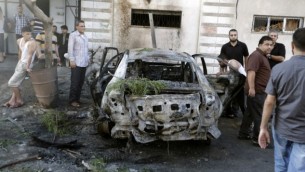 فلسطينيون يحتشدون حول سيارة محترقة في مدينة غزة في 19 يوليو، 2015، بعد أن دمرت سلسلة من الإنفجارات 5 مركبات في غزة تابعة لأعضاء في حركتي حماس والجهاد الإسلامي، بحسب شهود عيان ومصادر أمنية، في خضم توترات بين حكام القطاع الفلسطيني ومتطرفين إسلاميين. (AFP/MOHAMMED ABED)