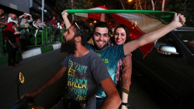 إيرانيون يلوحون بعلمهم في طهران خلال الاحتفال بتوقيع الاتفاق النووي، 14 يوليو 2015 (ATTA KENARE / AFP)