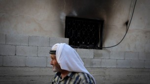 رجل فلسطيني يمر امام منزل عائلة دوابشة في بلدة دوما في الضفة الغربية، حيث أدى هجوم حريق من قبل إرهابيين يهود الى مقتل رضيع فلسطيني عمره 18 شهرا، 31 يوليو 2015 (FLASH90)