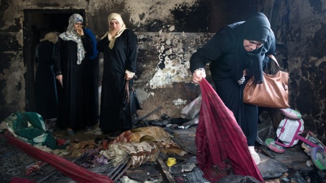 نساء فلسطينيات يتفحصن حطام منزل عائلة دوابشة في بلدة دوما في الضفة الغربية، 4 اغسطس 2015 (MENAHEM KAHANA / AFP)