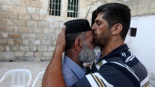 رجل فلسطيني يهنىء ويقبل جبين ناصر الدين علان، والد السجين محمد علان ، بعد أنباء  بشأن تعليق احتجازه، الصورة في منزل العائلة في مدينة نابلس بالضفة الغربية  19 آب،  2015. AFP PHOTO / JAAFAR ASHTIYEH