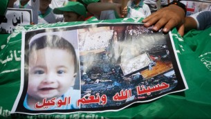 اطفال فلسطينيون يحملون نعش عليه صورة علي سعد دوابشة، 18 شهرا، الرضيع الذي قتل حرقا في الهجوم في بلدة دوما خلال مظاهرة في خان يونس في قطاع غزة، 1 اغسطس 2015 (Rahim Khatib / Flash 90)